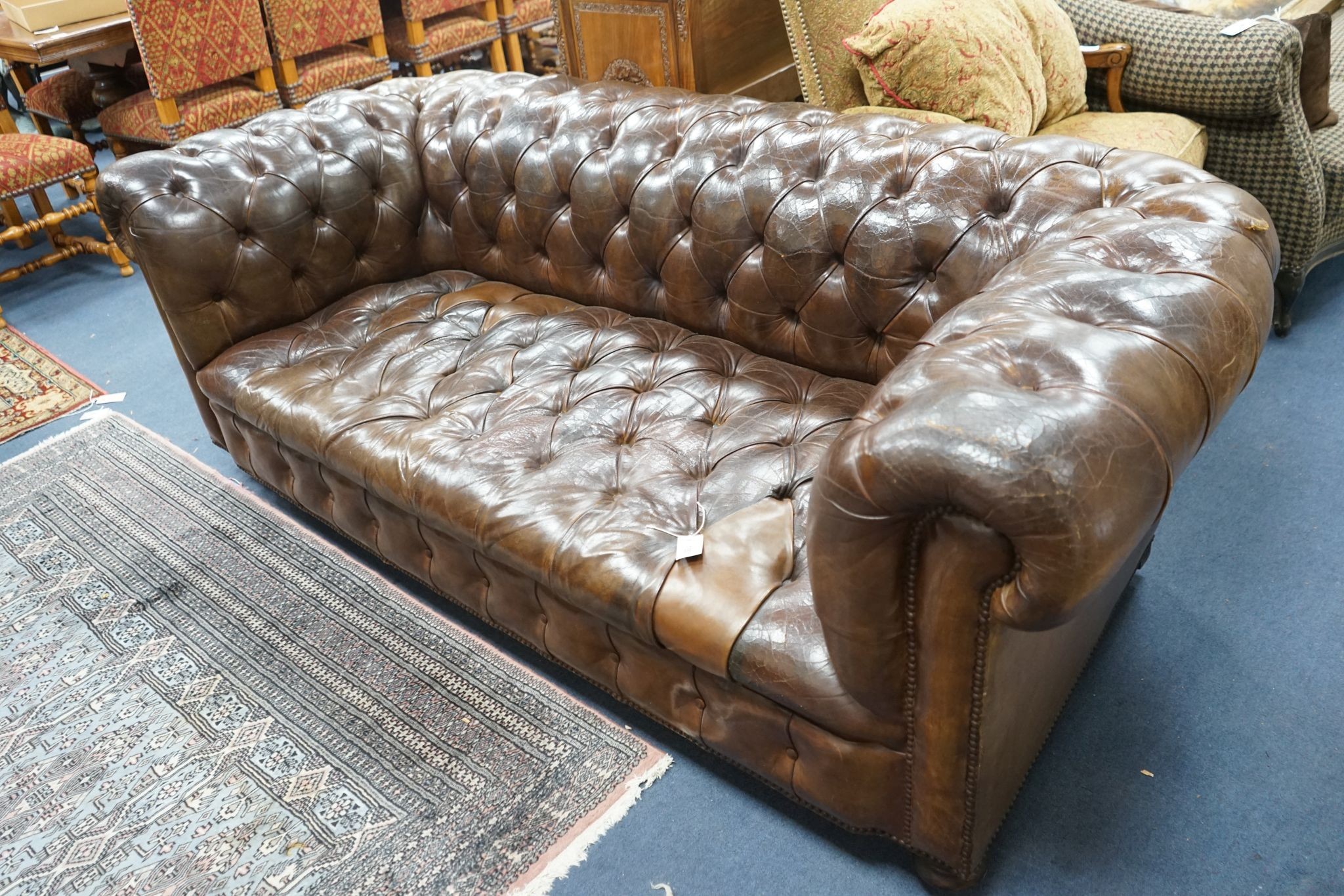 An early 20th century Chesterfield settee upholstered in deep buttoned brown leather, length 200cm, depth 90cm, height 72cm